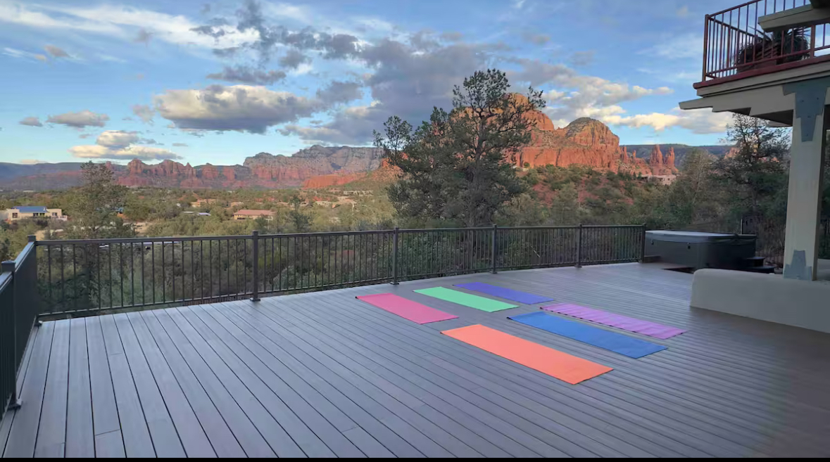 Spacious deck with yoga mats and hot tub, red rocks beyond